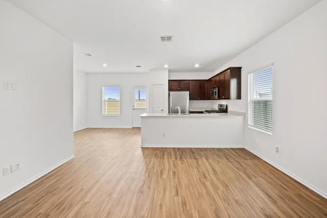 a living room with stainless steel appliances kitchen island hardwood floor sink stove and a window
