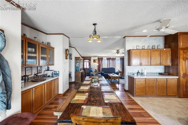 a very nice looking open kitchen with stainless steel appliances granite countertop a stove a refrigerator a dining table and chairs with wooden floor
