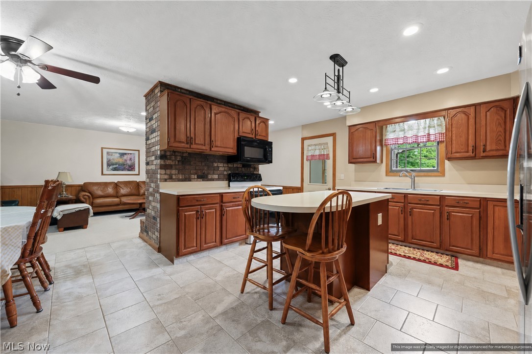 1835 Lynn Road Kent, OH 44240 - Photo 10 of 48 Spacious kitchen featuring wood-finish cabinetry, light-toned countertops, a central island with seating, a brick-textured half-wall, and tile flooring