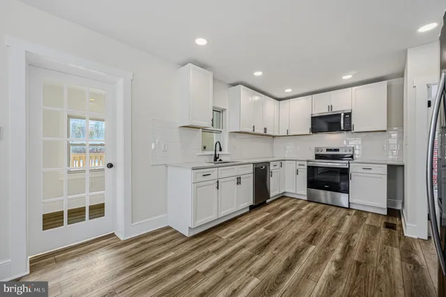 a kitchen with granite countertop white cabinets and stainless steel appliances