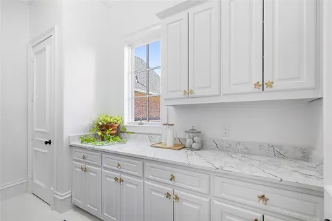 a kitchen with white cabinets and a window
