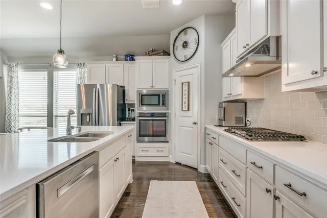 a kitchen with stainless steel appliances granite countertop a stove a refrigerator and a cabinets with wooden floor