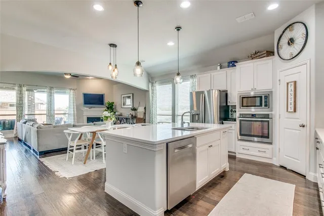 a kitchen with stainless steel appliances kitchen island a white cabinets and couches