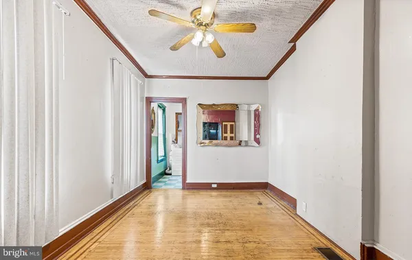 a view of an empty room with window and chandelier fan