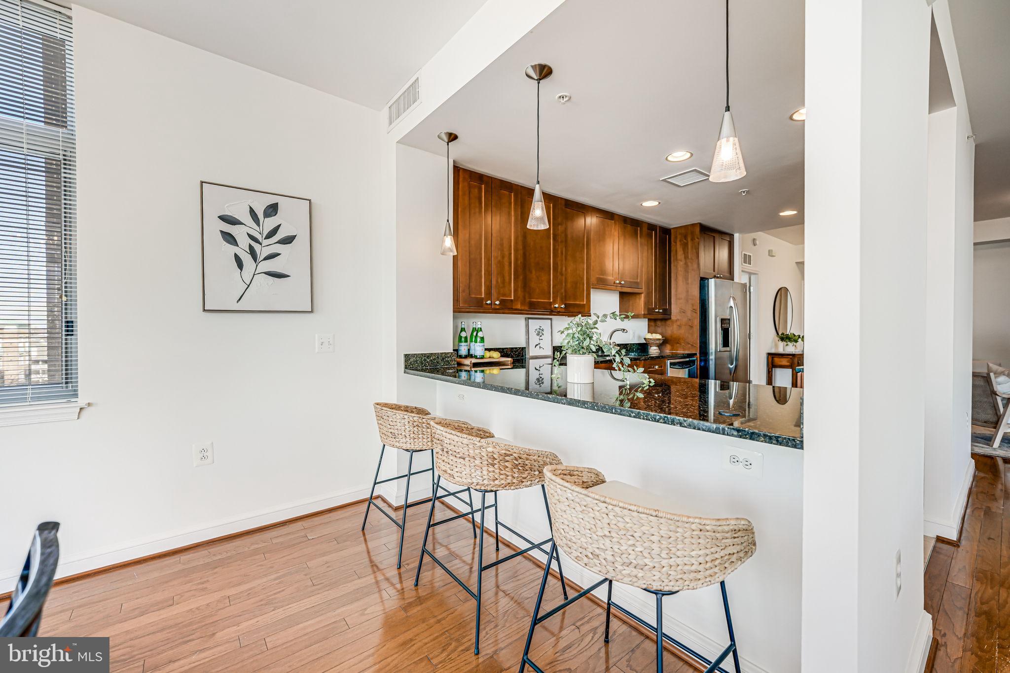 11990 Market Street, Unit 413 Reston, VA 20190 - Photo 18 of 82 a kitchen with stainless steel appliances kitchen island granite countertop a refrigerator a stove and a wooden floors