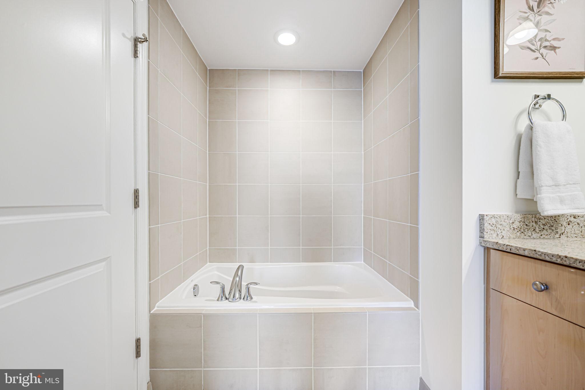 11990 Market Street, Unit 413 Reston, VA 20190 - Photo 24 of 82 a bathroom with a granite countertop sink a bathtub and shower