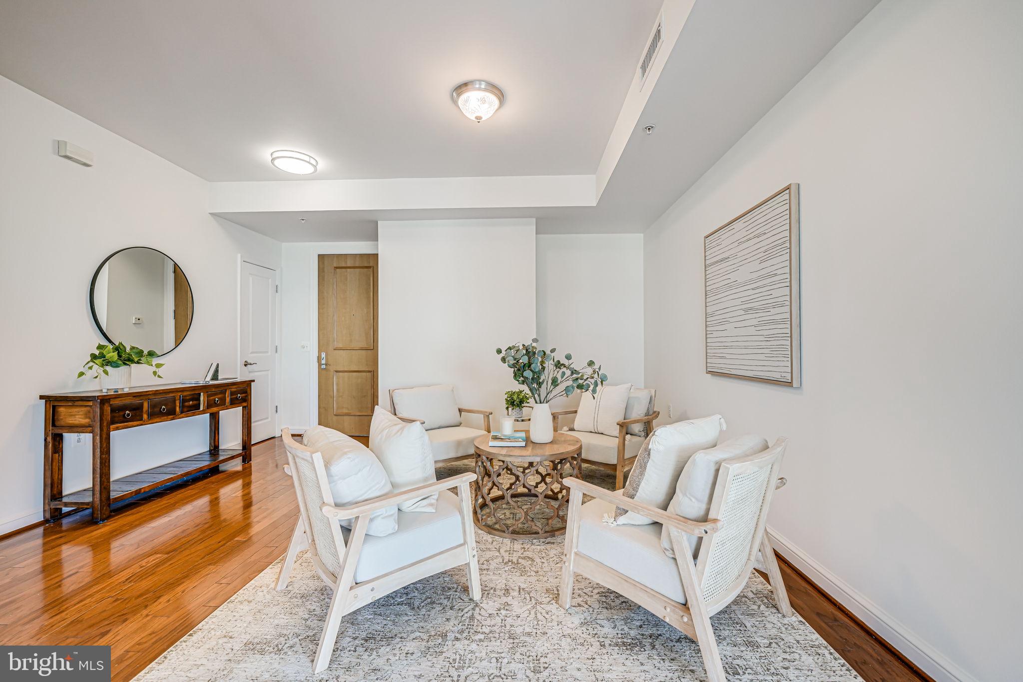 11990 Market Street, Unit 413 Reston, VA 20190 - Photo 7 of 82 a living room with furniture a mirror and a wooden floor