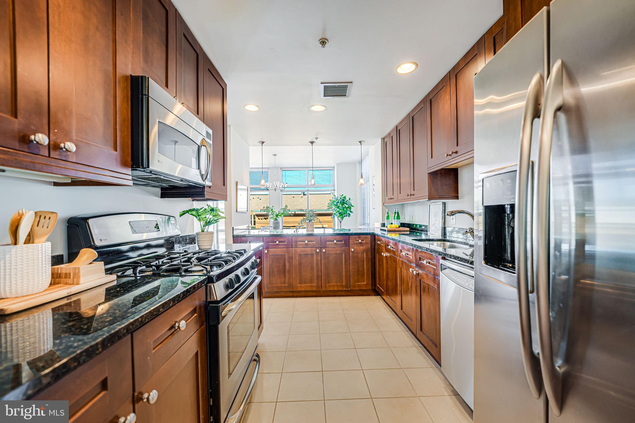 11990 Market Street, Unit 413 Reston, VA 20190 - Photo 9 of 82 a kitchen with stainless steel appliances granite countertop a refrigerator and a stove