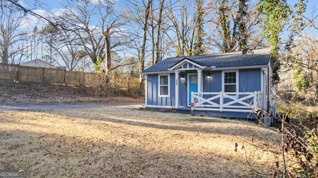 a view of a house with a small yard and large trees