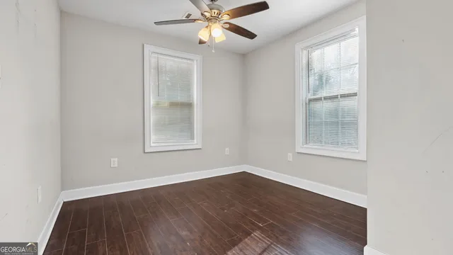 a view of an empty room with wooden floor and a window