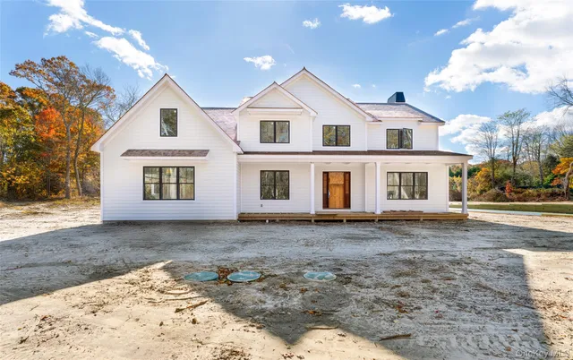 a view of a white house with a large tree in front of it