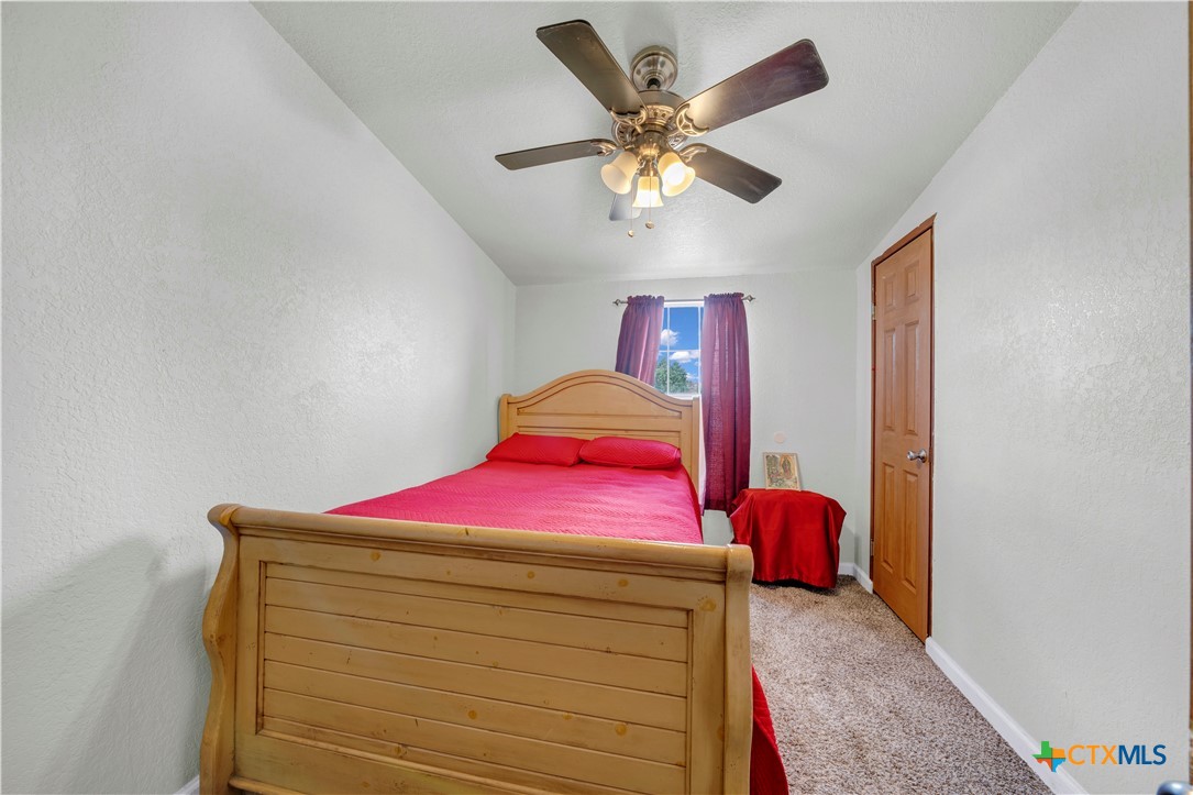 11706-11791 Kinney Road Atascosa, TX 78002 - Photo 23 of 25 a bedroom with a bed and a chandelier