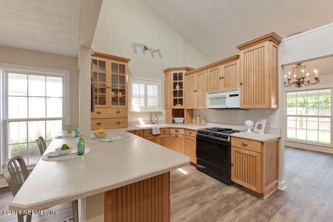 39 Solana Road Ponte Vedra Beach, FL 32082 - Photo 9 of 32 a kitchen with stainless steel appliances granite countertop a stove top oven a sink a dining table and chairs with wooden floor