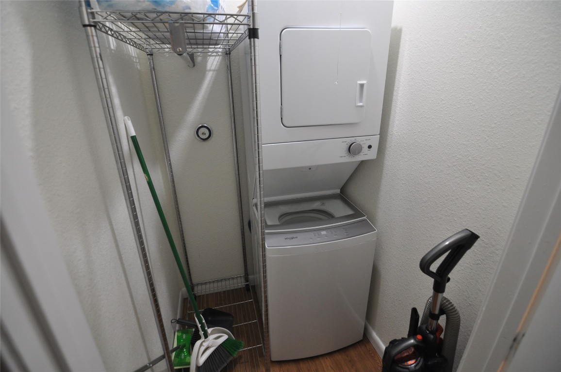 2207 Leon Street, Unit 201 Austin, TX 78705 - Photo 6 of 10 Laundry room with dark wood-style floors, stacked washer / dryer, and a textured wall