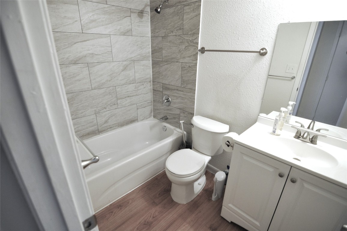 2207 Leon Street, Unit 201 Austin, TX 78705 - Photo 7 of 10 Bathroom featuring a textured wall, washtub / shower combination, vanity, and dark wood finished floors