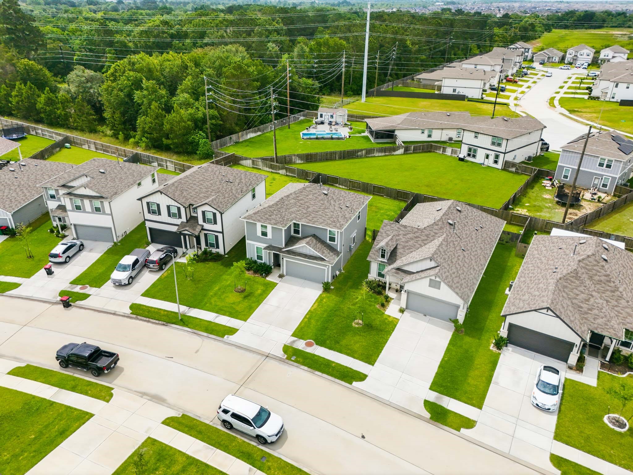 23427 Weir Box Road Hockley, TX 77447 - Photo 29 of 32 A elevated side-angle view emphasizing the home’s proximity to nature, featuring the mature tree line and open landscape bordering the back of the subdivision.
