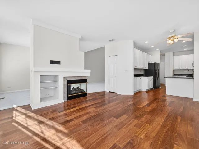 a view of kitchen and empty room with wooden floor