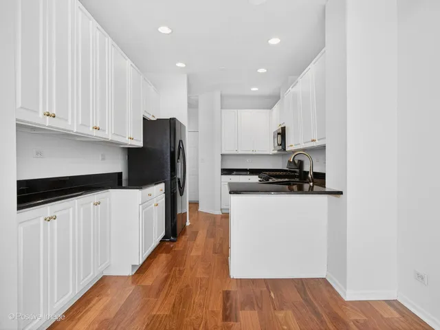 a kitchen with granite countertop white cabinets and stainless steel appliances