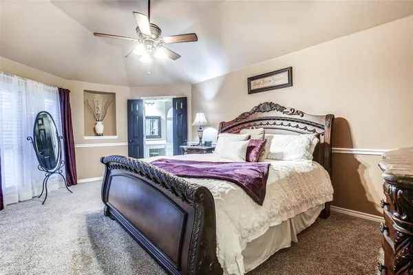 a bedroom with a bed a chandelier and dresser