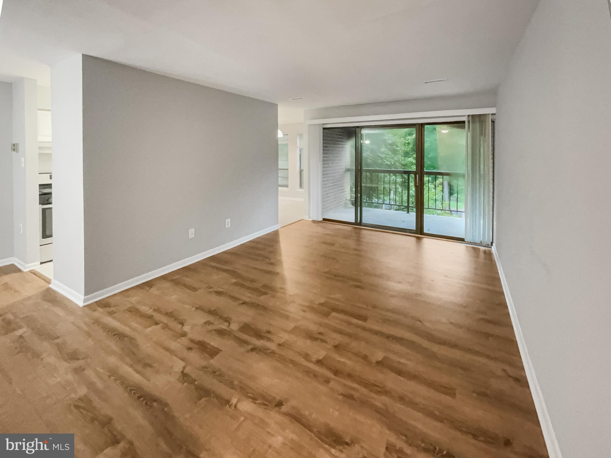 11204 Chestnut Grove Square, Unit 206 Reston, VA 20190 - Photo 4 of 18 a view of an empty room with wooden floor and a window