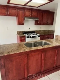 a kitchen with granite countertop wood cabinets stainless steel appliances and a sink