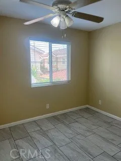 an empty room with a chandelier fan and windows