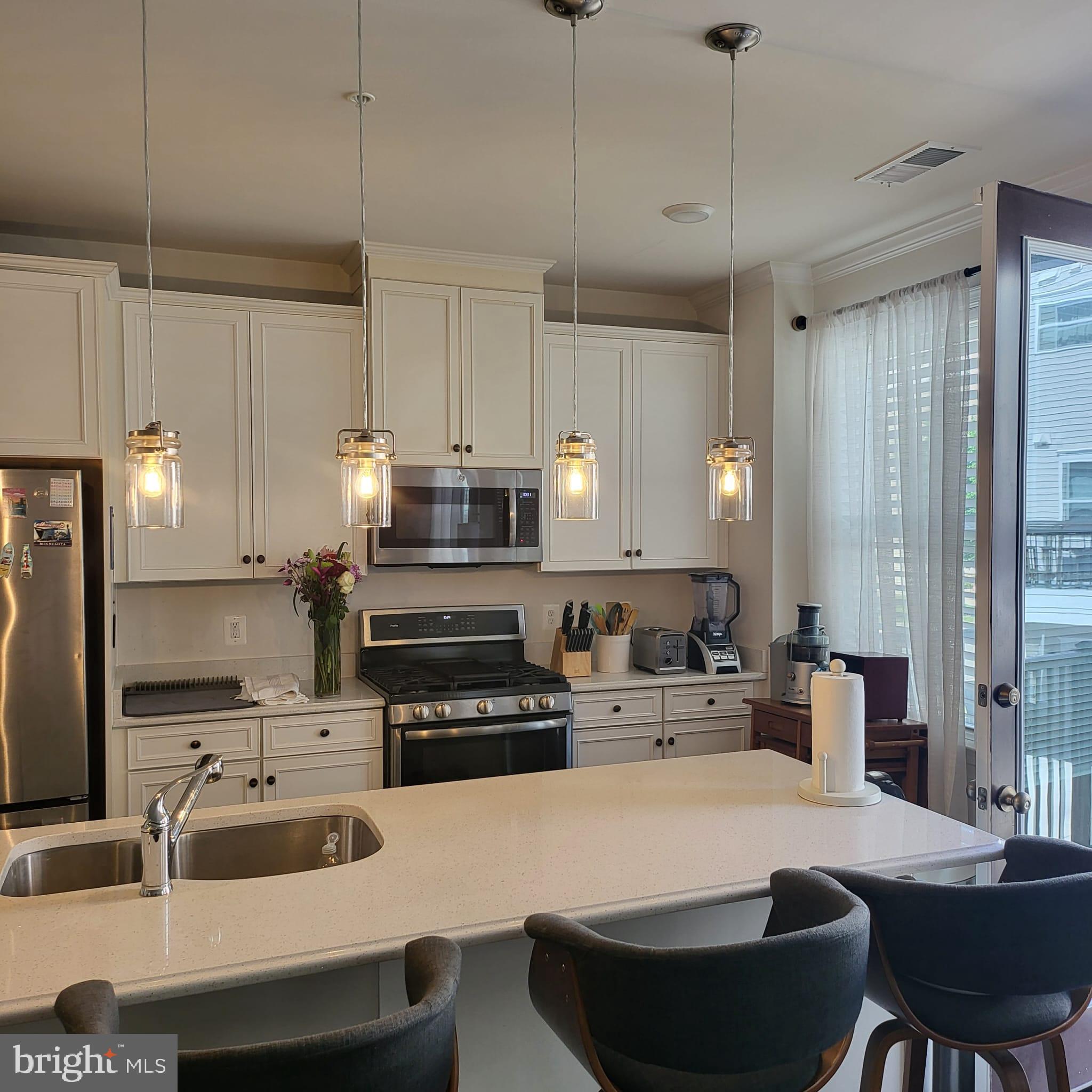 24626 Cable Mill Terrace Aldie, VA 20105 - Photo 6 of 46 a kitchen with stainless steel appliances a stove a sink a microwave a refrigerator and white cabinets with wooden floor