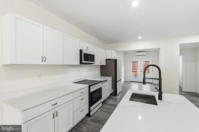 a kitchen with white cabinets a sink dishwasher and a stove with wooden floor