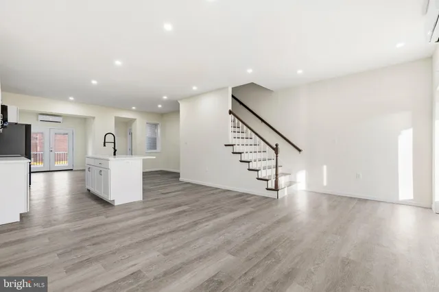 a view of an empty room with wooden floor and stairs
