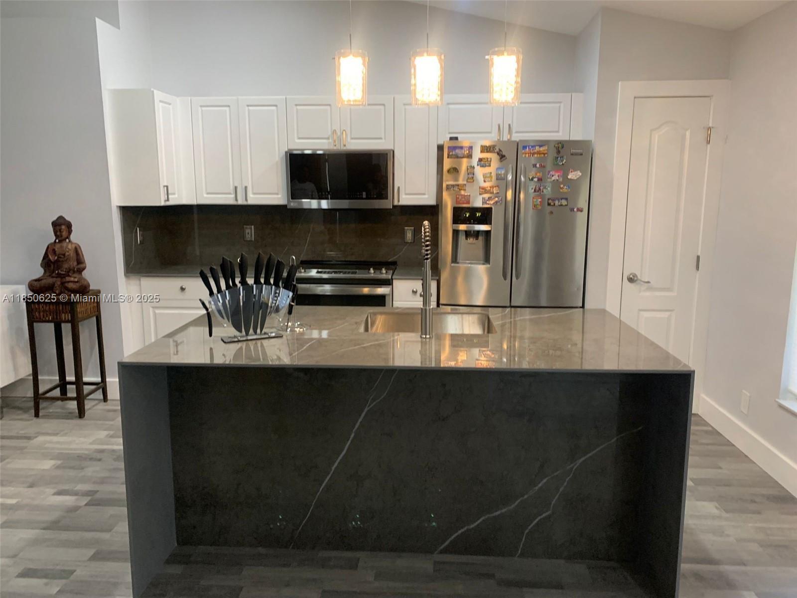 442 Conlee Street Lehigh Acres, FL 33974 - Photo 19 of 79 a kitchen with stainless steel appliances a kitchen island hardwood floor sink and stove