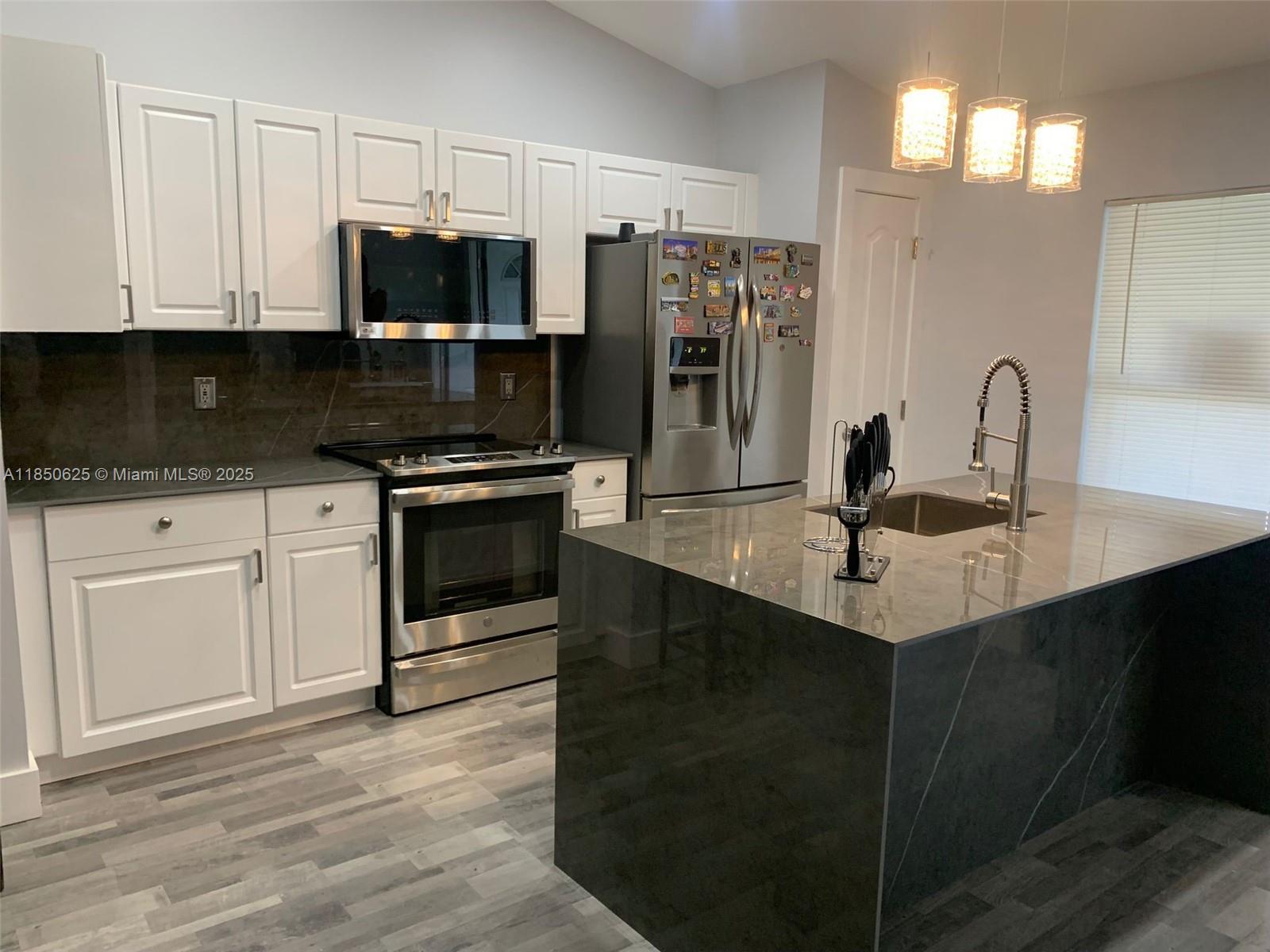 442 Conlee Street Lehigh Acres, FL 33974 - Photo 2 of 79 a kitchen with stainless steel appliances a sink cabinets and a stove top oven