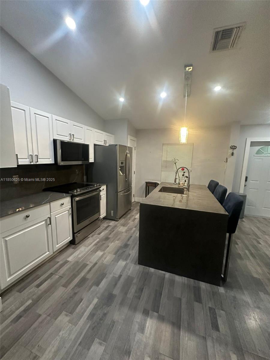 442 Conlee Street Lehigh Acres, FL 33974 - Photo 26 of 79 a living room with stainless steel appliances kitchen island granite countertop a refrigerator a stove top oven a sink dishwasher and wooden floor