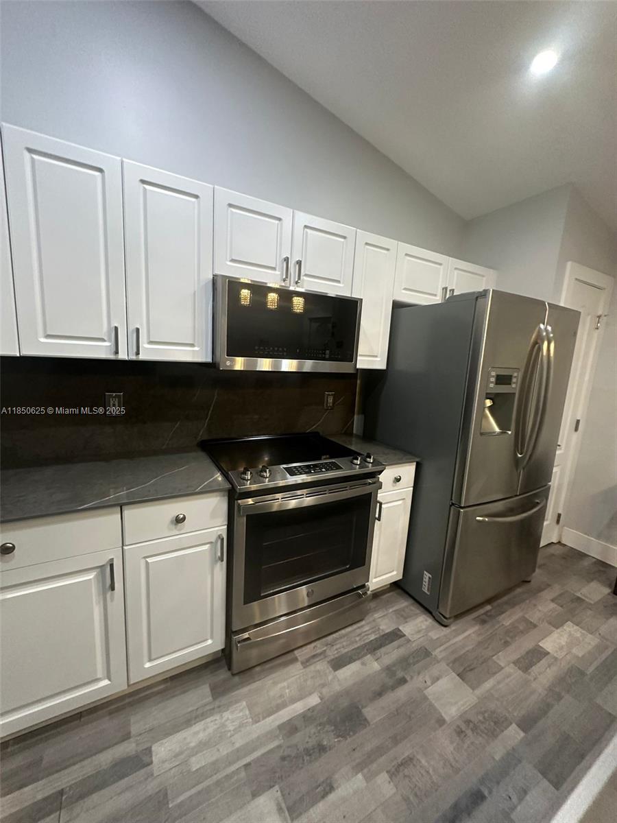 442 Conlee Street Lehigh Acres, FL 33974 - Photo 28 of 79 a kitchen with stainless steel appliances granite countertop a refrigerator and a stove