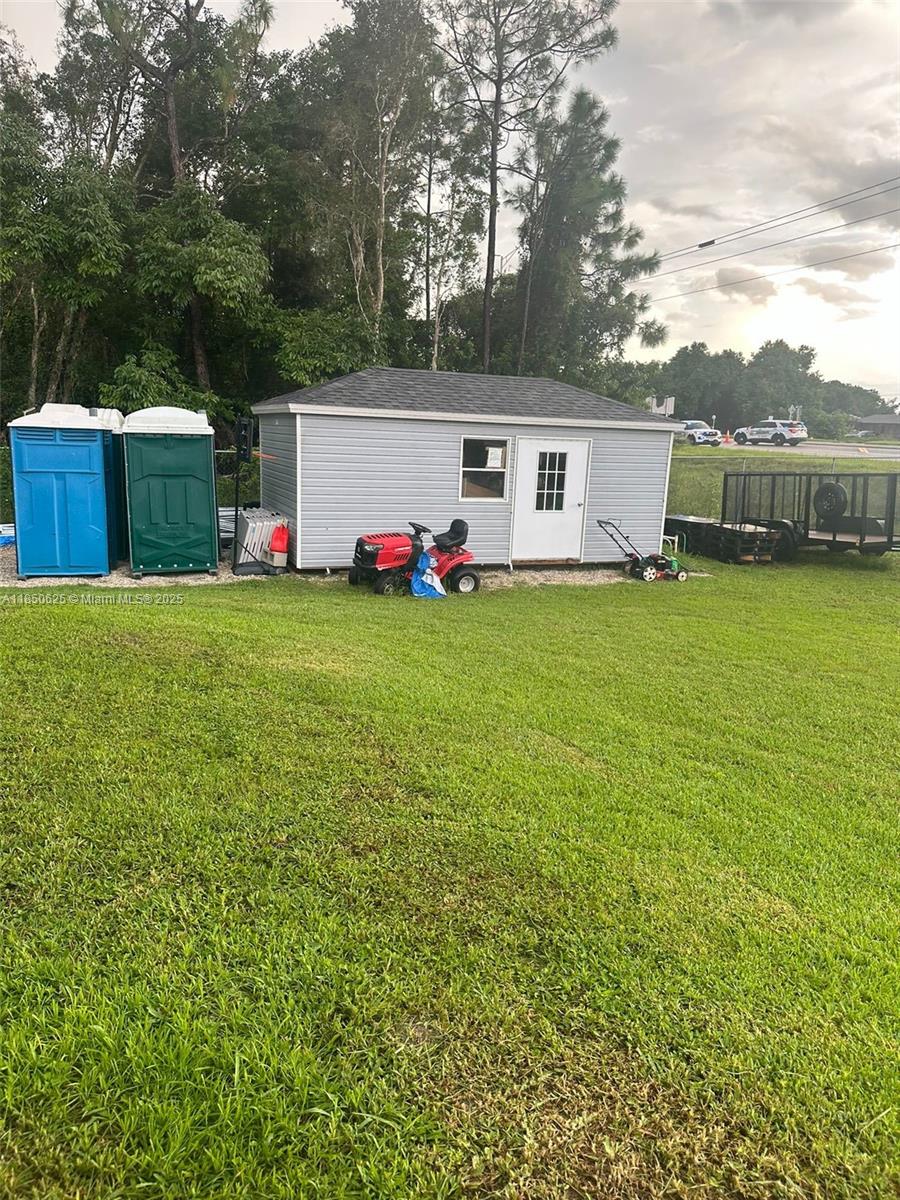 442 Conlee Street Lehigh Acres, FL 33974 - Photo 30 of 79 a view of a white house in front of a big yard with potted plants and large trees