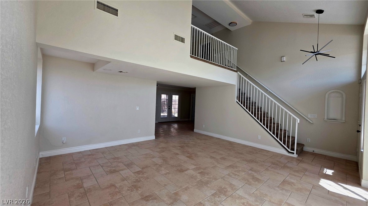 2155 Athol Way Laughlin, NV 89029 - Photo 14 of 19 A spacious living area features high ceilings, a grand staircase, and a modern chandelier, all complemented by durable tile flooring.