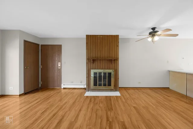 an empty room with wooden floor chandelier fan and windows