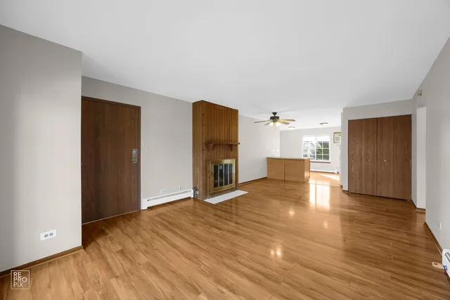 a view of a livingroom with a fireplace a ceiling fan and wooden floor