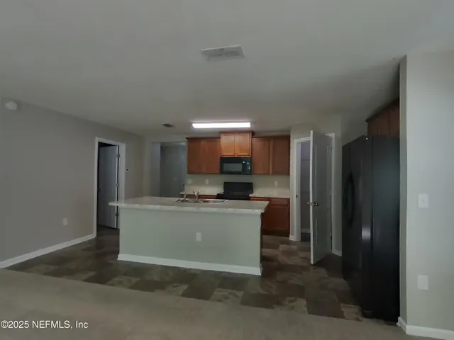 a room with kitchen island a sink a stove and a refrigerator
