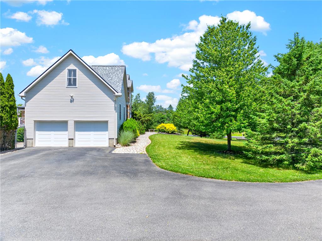 220 Pennbrook Road Stroudsburg, PA 18360 - Photo 49 of 60 A well-maintained driveway leads to a pristine garage, surrounded by verdant trees and a clear blue sky.