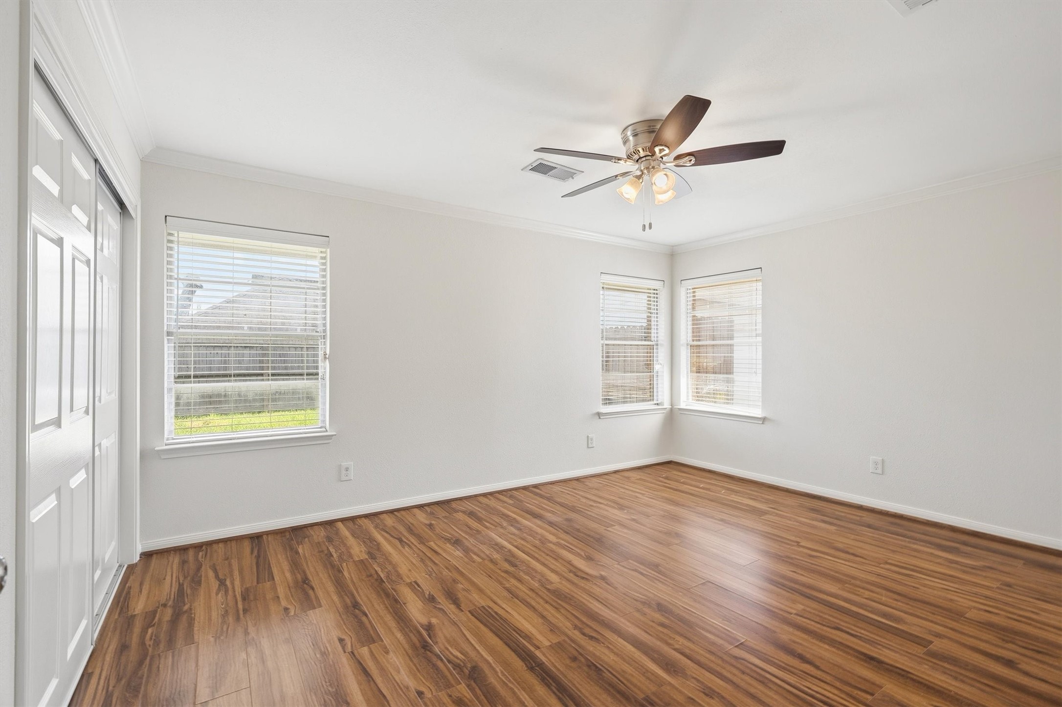 3331 Arbor Street Houston, TX 77004 - Photo 22 of 30 This spacious primary bedroom features laminate wood flooring, neutral walls, a ceiling fan, and ample natural light from three windows.