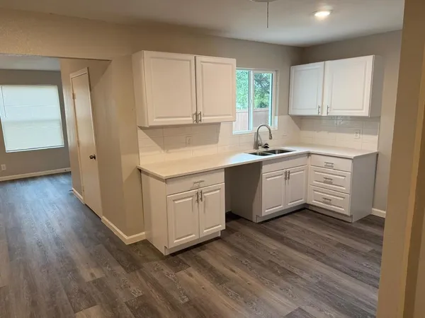 a kitchen with a sink cabinets wooden floor and stainless steel appliances