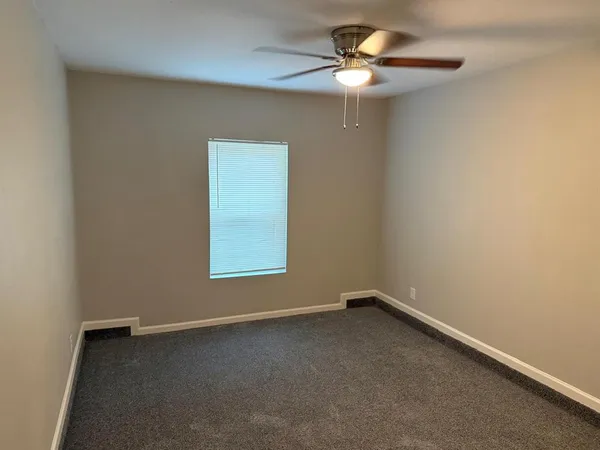 an empty room with a window and a fan