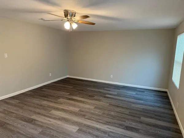 a view of a room with wooden floor and a ceiling fan