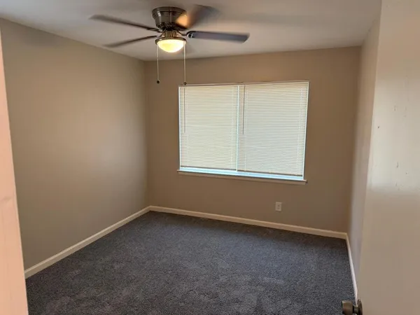 an empty room with a window and a fan