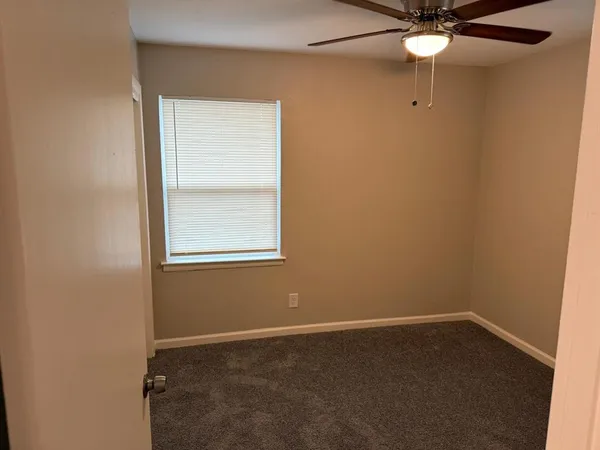 an empty room with a window and a fan