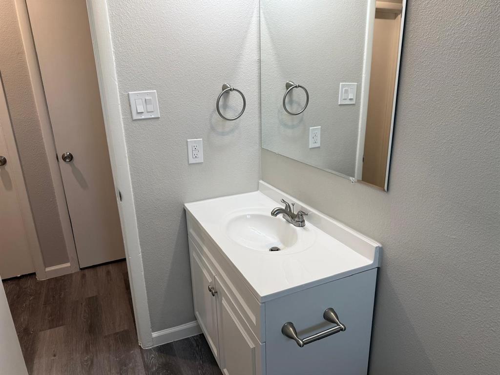 925 Bluewood Drive Dallas, TX 75232 - Photo 7 of 33 Bathroom featuring a textured wall, dark wood finished floors, and vanity