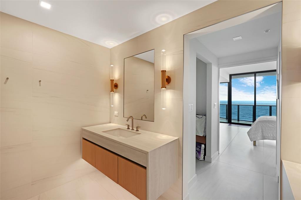 900 North Ocean Boulevard, Unit 906 Pompano Beach, FL 33062 - Photo 12 of 33 a en suite bathroom with a sink and a mirror