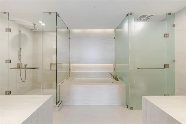 a bathroom with a tub shower sink and mirror