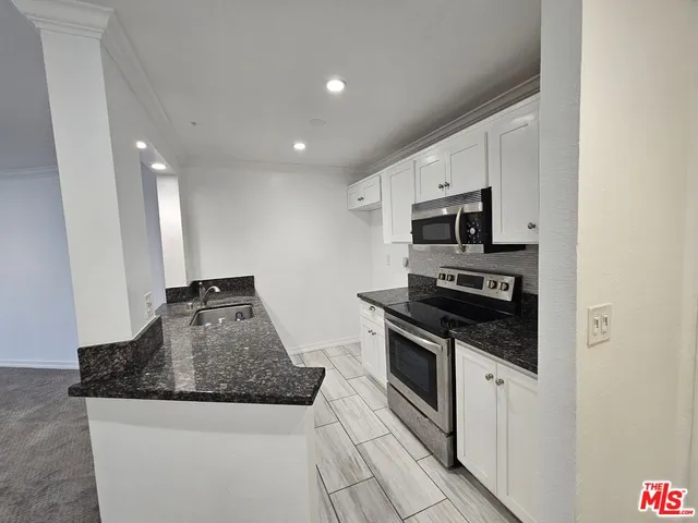 a kitchen with granite countertop a stove sink and microwave