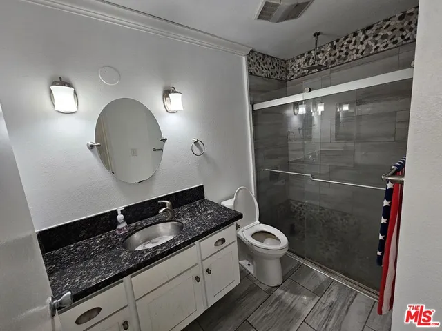 a bathroom with a granite countertop sink a toilet a mirror and shower